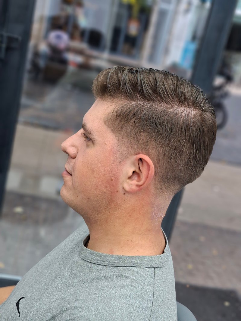 Close-up van een klant met een zijscheiding en een korte fade in de nek